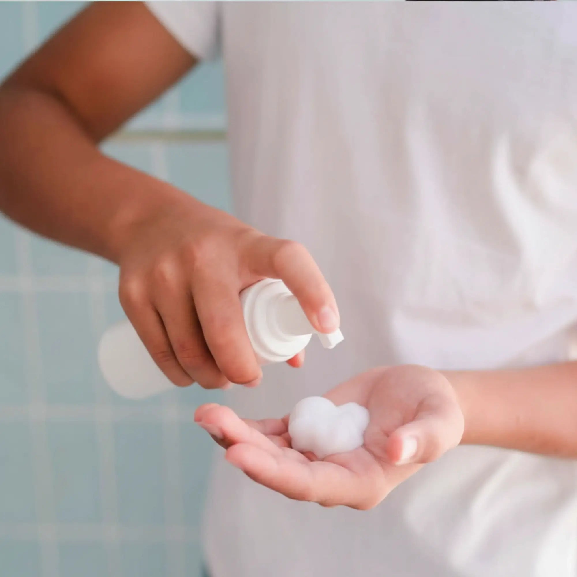 14 year old boy pumping petite skin co face cleansing foam in a bathroom setting.