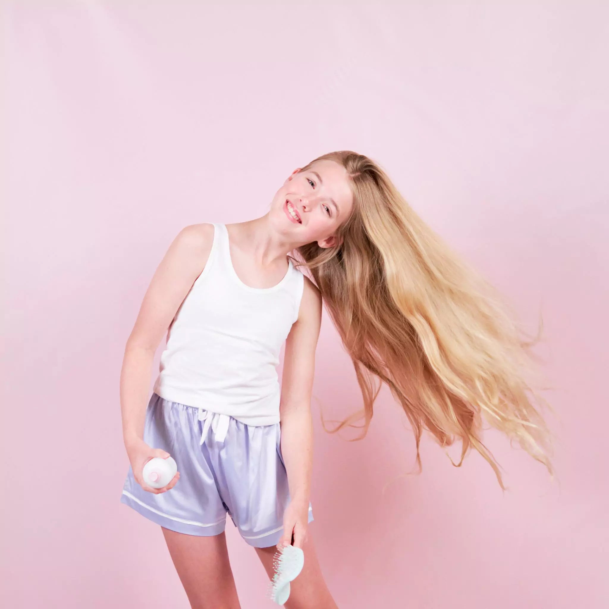 11 year old girl brushing her hair with the Petite Skin Co. Detangling Brush and Nourishing Detangler.