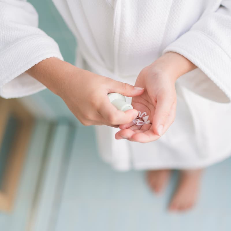 Child in a white robe dispensing a gentle face cleanser into their hand as part of the Skin Harmony Routine, Australian made natural skincare designed for 7 to 14 year olds. Good Skin Habits Start Early.