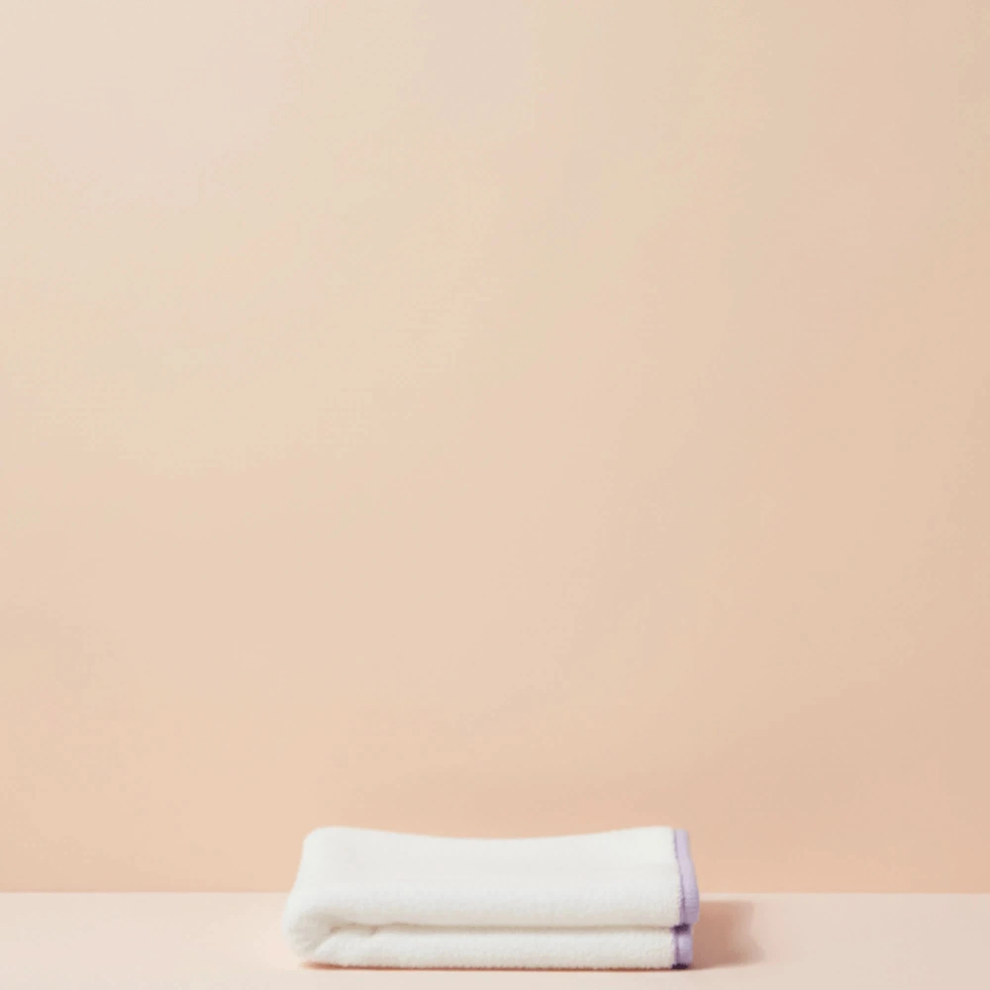 Folded white towel on a beige background