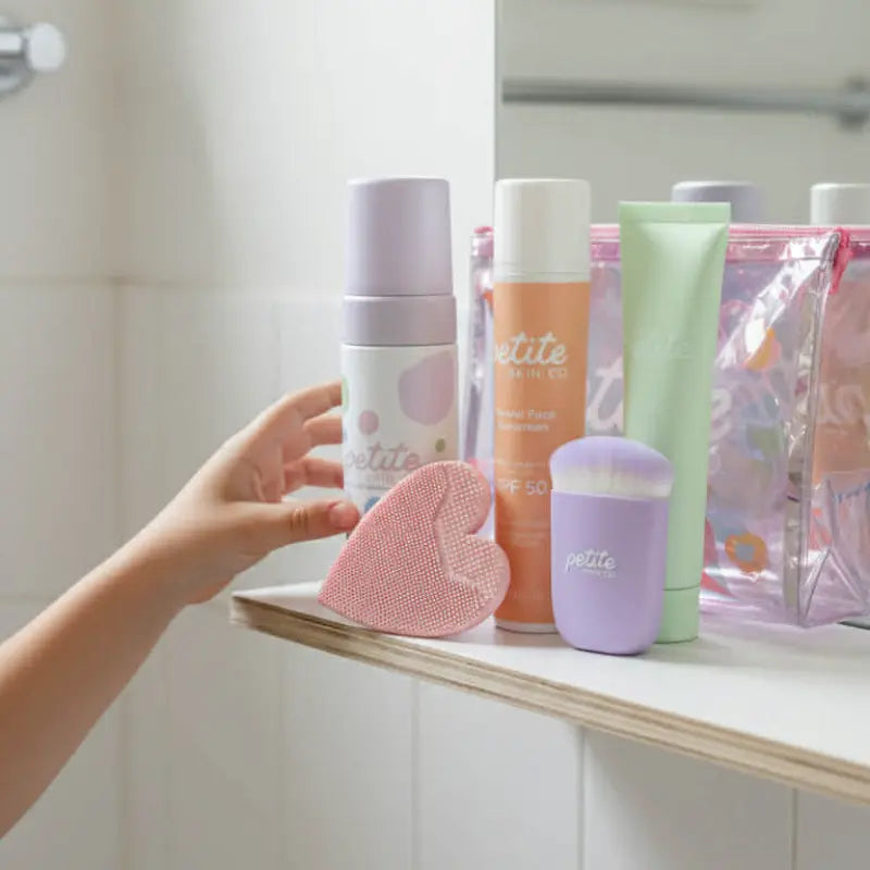 Child's hand reaching for a purple Sunscreen Applicator Brush among gentle Australian made skincare products for 7 to 14 year olds promoting good skin habits start early.