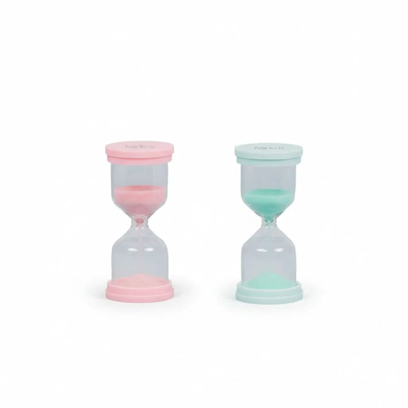 Two 60 Second Skincare Timer hourglasses in pink and mint colors made from sturdy borosilicate glass with sparkly silica, designed to promote good skin habits in children aged 7 to 14.
