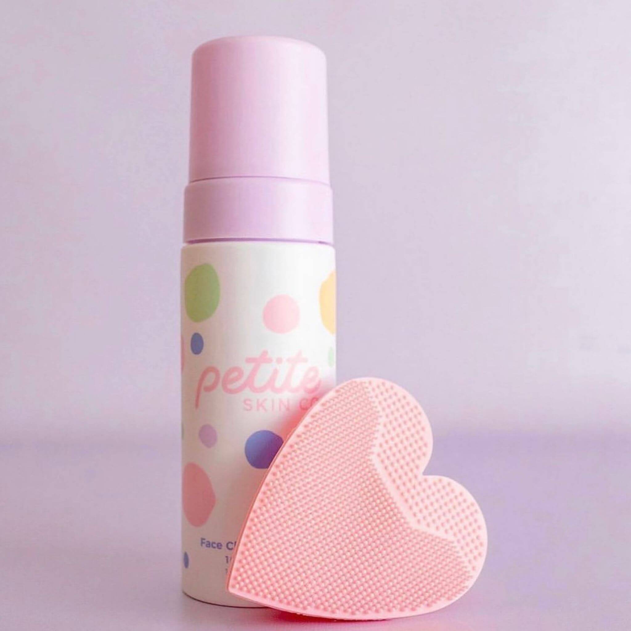 face cleansing foam and buffer on pink background