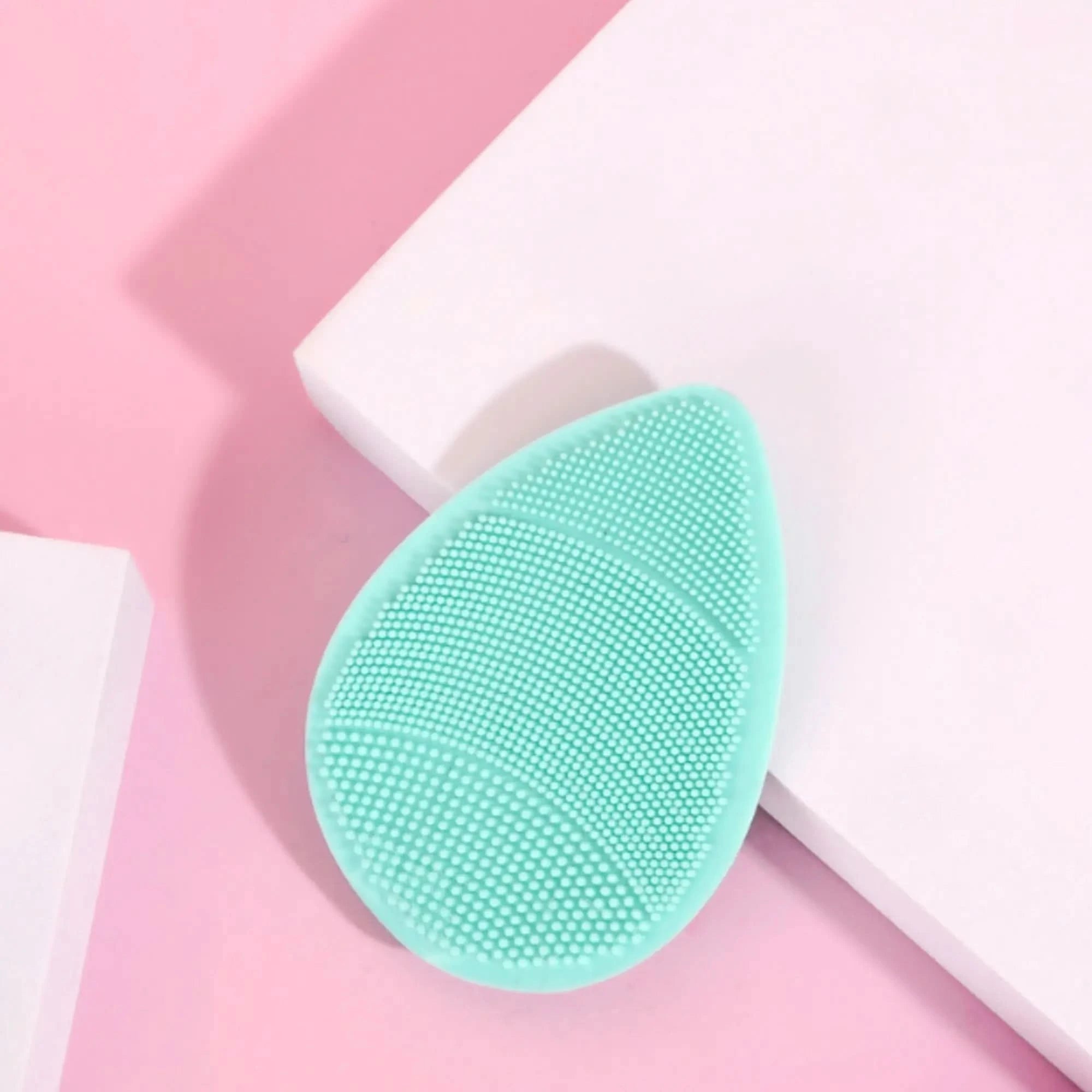 Teal silicone skin buffer on a pink and white background