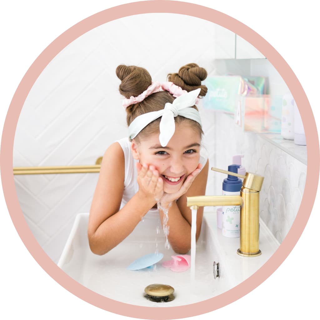 Girl washing face splashing water over basin wearing pyjamas