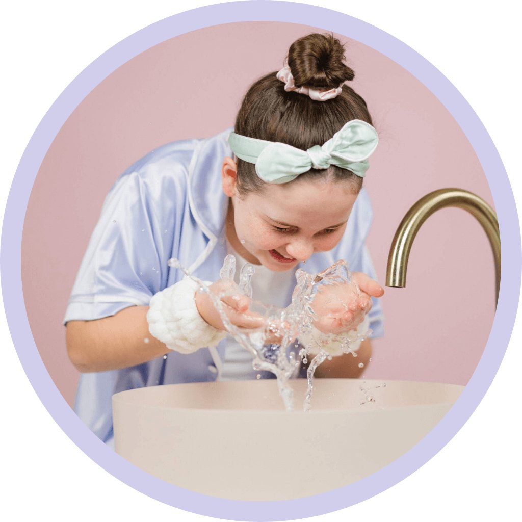 Girl washing face splashing water wearing pyjamas over sink
