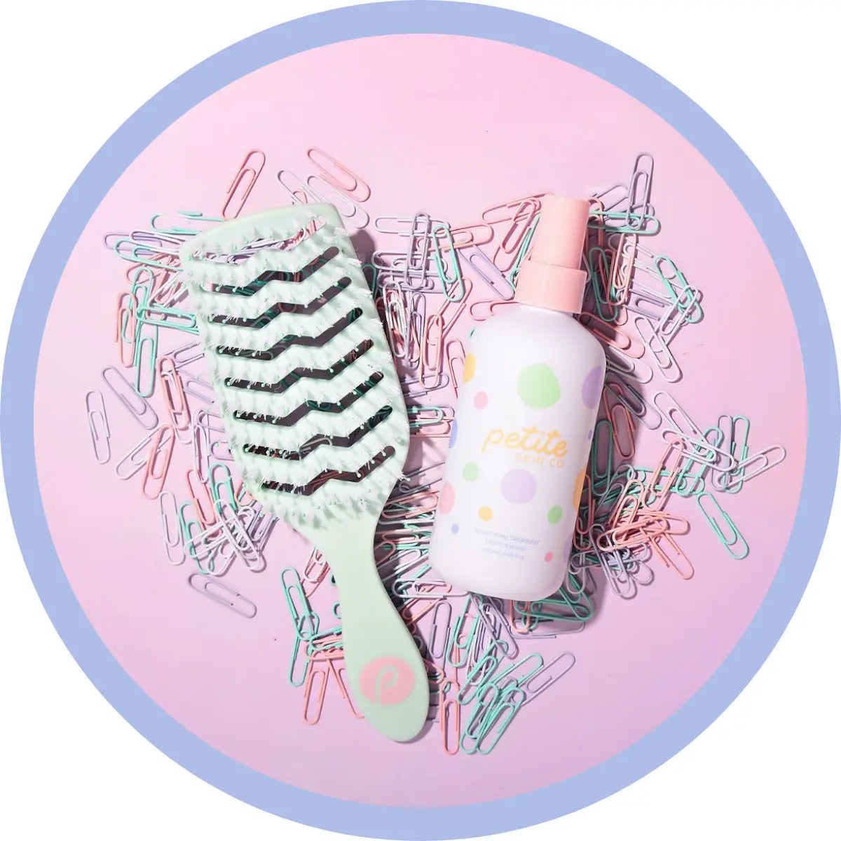 Petite Skin Co. brush and detangling spray on paper clips on pink background