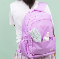 Young person carrying a lavender backpack with the Tangle-Free Duo hair detangler spray and dual-bristle brush visible in the front pocket, Australian made natural care for ages 7 to 14, good skin habits start early.