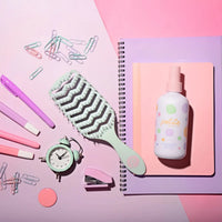 Tangle-Free Duo with nourishing detangler spray and dual-bristle brush on pastel notebooks, styled with pink and mint stationery, Australian made natural hair care for kids.