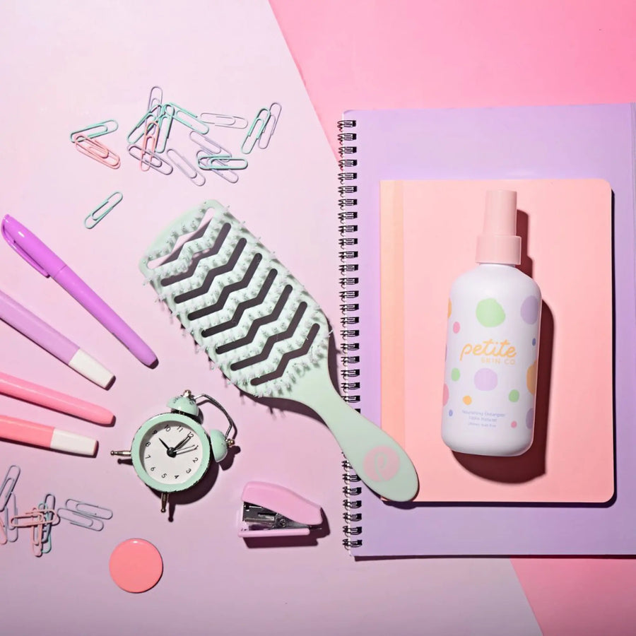 Tangle-Free Duo with nourishing detangler spray and dual-bristle brush on pastel notebooks, styled with pink and mint stationery, Australian made natural hair care for kids.