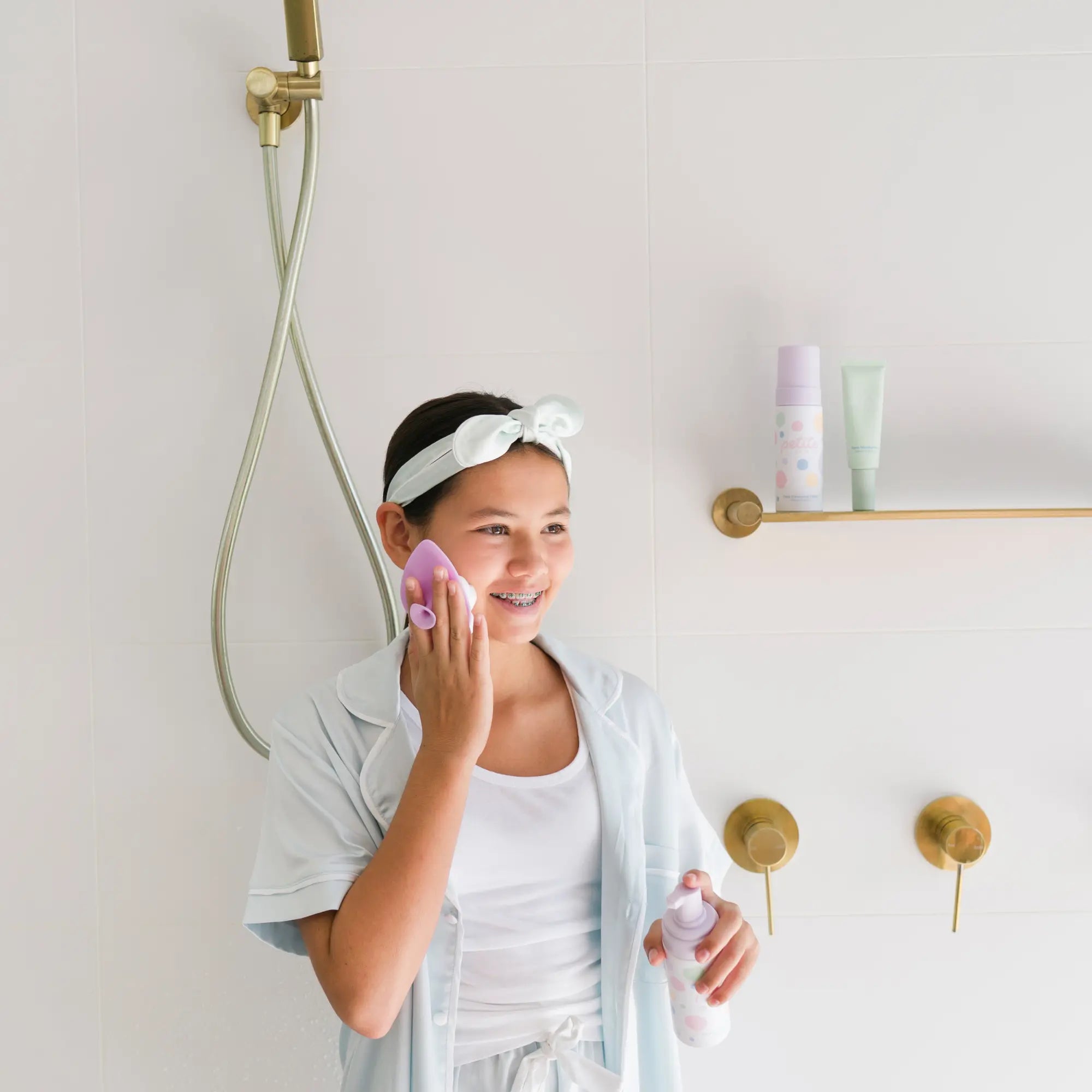 Young girl in bathroom using Teardrop Shape Skin Buffers made of soft food-grade silicone to gently cleanse face, promoting good skin habits early with Australian made skincare.