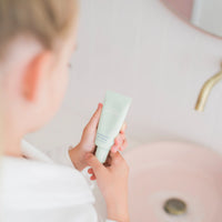Child holding a tube of Face Moisturiser designed for 7 to 14 year olds, highlighting Australian made, natural skincare promoting good skin habits start early.