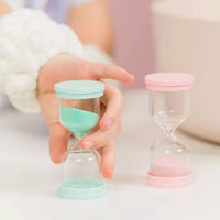 Two Australian made 60 Second Skincare Timer sandglasses in pastel pink and mint, designed to encourage good skin habits and gentle cleansing for 7 to 14 year olds.