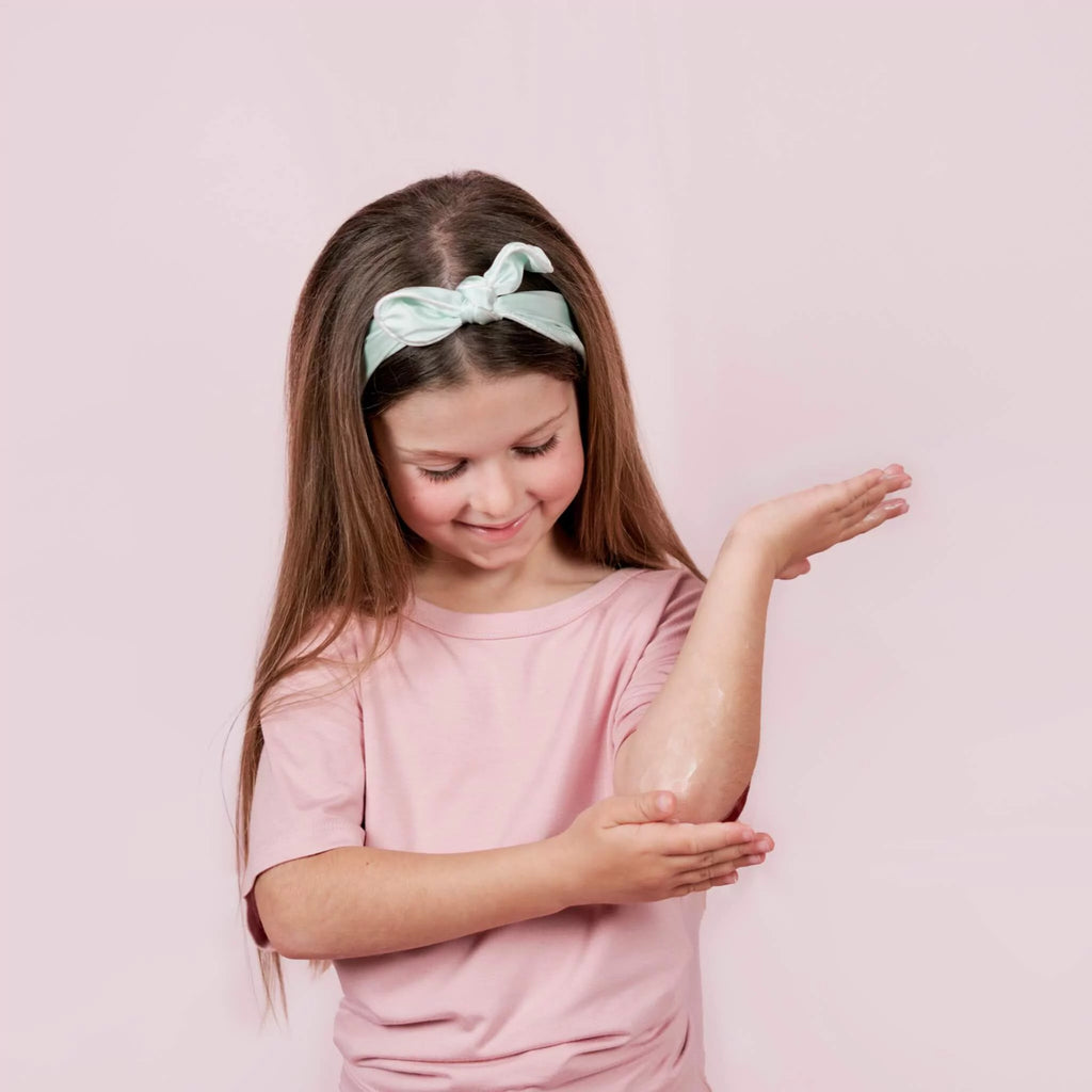8 year old girl putting Petite Skin Co. body cream into dry elbows