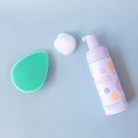 Teardrop Shape Skin Buffers in soft silicone next to a pump bottle of gentle face cleansing foam and foam on a light blue surface, Australian made for 7 to 14 year olds.