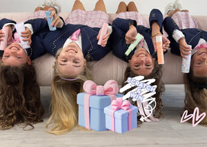 Children lying on a couch with decorative gift boxes and ribbons in front of them.