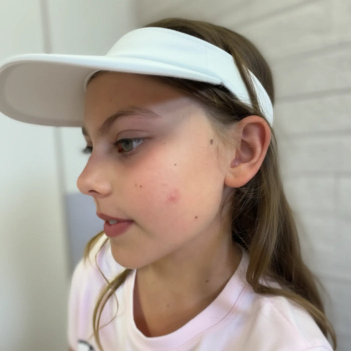 Young girl wearing a white visor and light pink shirt with clear skin showing mild blemishes, promoting Clear Skin Essentials | Confetti Collection, Australian made, natural skincare for 7 to 14 year olds. Good Skin Habits Start Early.