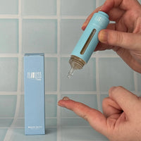 Person dispensing clear Blemish Serum from a blue bottle onto fingertip, next to matching light blue packaging, Australian made natural skincare for 7 to 14 year olds, good skin habits start early.