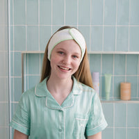 Girl wearing a soft towelling headband with lilac trim, designed to keep hair off the face during skincare routines, made for 7 to 14 year olds and Australian made.