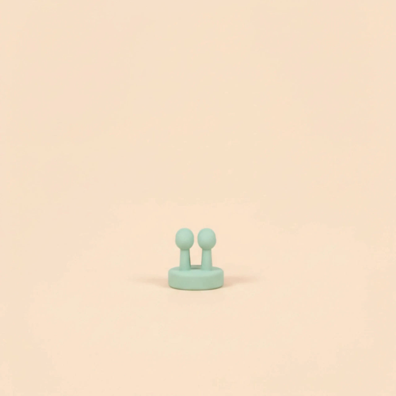 A small mint green silicone applicator brush with two rounded tips, designed to gently apply "The Sun Smart Set" sunscreen for Australian made, natural skincare for 7 to 14 year olds, promoting good skin habits early.