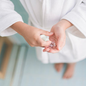 Child in a white robe dispensing a gentle face cleanser into their hand as part of the Skin Harmony Routine, Australian made natural skincare designed for 7 to 14 year olds. Good Skin Habits Start Early.