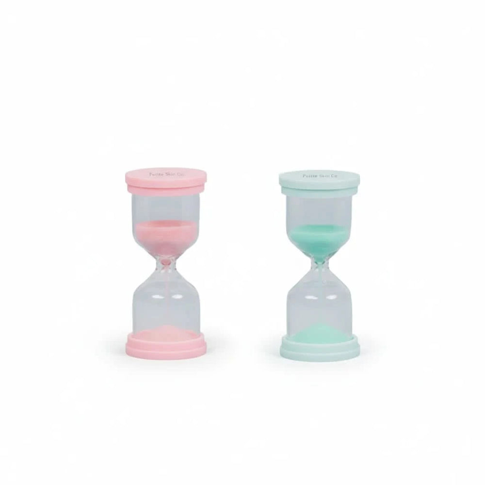 Two 60 Second Skincare Timer hourglasses in pink and mint colors made from sturdy borosilicate glass with sparkly silica, designed to promote good skin habits in children aged 7 to 14.