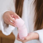 girl wearing white robe holding pink deodorant
