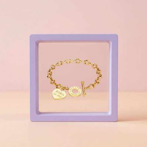 Gold bracelet with charms on a pink background