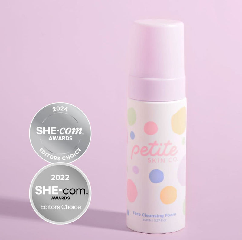 A bottle of Petite Skin Co. Face Cleansing Foam with multicolored dots design, placed against a light blue tiled background.